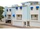 Three-story townhome features a modern facade with blue awnings and a white garage door at 1413 Bayshore Blvd # 11, Dunedin, FL 34698