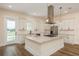 Bright kitchen features white cabinets, island with cooktop, stainless steel appliances, and wood floors at 1413 Bayshore Blvd # 11, Dunedin, FL 34698