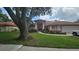 Beautifully landscaped home with a well-manicured lawn, red trim, and covered entry at 16502 Windsor Park Dr, Lutz, FL 33549