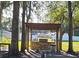 Outdoor kitchen features a stone base, stainless steel grill and prep area for gatherings amid mature landscaping at 16502 Windsor Park Dr, Lutz, FL 33549