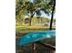 A serene lakeside view featuring trees, a picnic table, and a swing on the shore of a tranquil lake at 16502 Windsor Park Dr, Lutz, FL 33549