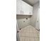Compact laundry area with white cabinets, neutral walls and tiled flooring, offering functionality and storage at 16502 Windsor Park Dr, Lutz, FL 33549