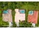 Aerial view of three homes with screened-in pools, tile roofs, lush landscaping, and driveways at 17818 Arbor Greene Dr, Tampa, FL 33647