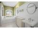 Bathroom featuring a soaking tub, pedestal sinks, and beadboard paneling at 17818 Arbor Greene Dr, Tampa, FL 33647