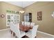Elegant dining room with a large table, white chairs, and a decorative light fixture at 17818 Arbor Greene Dr, Tampa, FL 33647