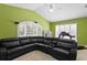 Cozy living room with vaulted ceiling, large leather couch, and bright natural light at 17818 Arbor Greene Dr, Tampa, FL 33647