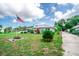 Quaint single-Gathering house with a metal roof, green lawn, landscaping, and an American flag in the yard at 2060 Saffold Park Dr, Ruskin, FL 33570