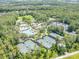 Aerial view of tennis courts, community pool and clubhouse nestled in a vibrant, green landscape at 27546 Stonecreek Way, Wesley Chapel, FL 33544