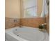 Close-up of a white bathtub under a window with decorative tile and hardware at 27546 Stonecreek Way, Wesley Chapel, FL 33544