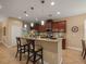 Open-concept kitchen bar featuring granite countertops, wood cabinetry, pendant lighting, and comfortable bar stool seating at 27546 Stonecreek Way, Wesley Chapel, FL 33544