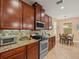Elegant kitchen features dark wood cabinetry, granite counters, stainless steel appliances, and tiled backsplash at 27546 Stonecreek Way, Wesley Chapel, FL 33544