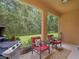 Covered patio with comfortable seating, an outdoor grill and view of the natural landscape at 27546 Stonecreek Way, Wesley Chapel, FL 33544