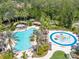 Aerial view of a resort-style pool, splash pad, and lounging area surrounded by lush greenery at 27546 Stonecreek Way, Wesley Chapel, FL 33544