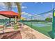 Outdoor pickleball court featuring seating and a shade structure with a manicured walkway at 301 Kings Blvd # 130, Sun City Center, FL 33573