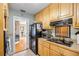 Galley kitchen with wood cabinets, black appliances, and an opening leading to other living spaces at 3107 S Emerson St, Tampa, FL 33629