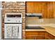 Galley kitchen featuring natural wood cabinetry, white appliances, and brick accent wall at 327 Sunnyside Rd, Temple Terrace, FL 33617