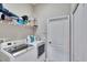 Well-organized laundry room featuring a washer, dryer, storage shelf, and a nearby door at 3411 Knoxville Pl, Plant City, FL 33566
