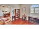 Cozy living room features hardwood floors, a vintage bookcase, and natural light from a window with shutters at 3411 Knoxville Pl, Plant City, FL 33566