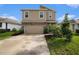 Two-story home with a tan exterior, stone accents, a two-car garage and landscaped front yard at 3528 Maple Grove Way, Plant City, FL 33565