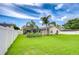 Large, grassy backyard with white fencing, tropical landscaping, and a screened-in pool area, ideal for Gathering fun at 4211 Elba Pl, Valrico, FL 33596