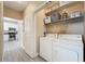 A functional laundry room with a washer, dryer, and shelving for storage, next to a kitchen space at 4221 W Spruce St # 2218, Tampa, FL 33607