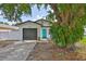 Charming home featuring a gray garage door and a bright blue front door under a shady tree at 4489 57Th N Ave, St Petersburg, FL 33714