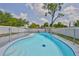 Kidney-shaped pool surrounded by a secure safety fence in a sunny backyard with mature trees at 4489 57Th N Ave, St Petersburg, FL 33714