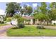 Charming single-story home featuring a brick driveway, lush landscaping, and a vibrant green front door at 5262 25Th N Ave, St Petersburg, FL 33710