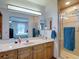 Bright bathroom with wood cabinets, a shower, and a clear view of the main bedroom at 5755 Yorkshire Dr, Zephyrhills, FL 33542