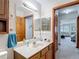 Neutral bathroom with double-door access, a decorative mirror, and a wood vanity at 5755 Yorkshire Dr, Zephyrhills, FL 33542