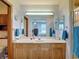 Well-lit bathroom with wood cabinets, a shower, and a clear view of the main bedroom at 5755 Yorkshire Dr, Zephyrhills, FL 33542