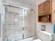 Bright bathroom featuring tiled walls, a shower with a glass enclosure, and a storage cabinet at 5755 Yorkshire Dr, Zephyrhills, FL 33542