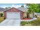 Charming single-story home showcasing a brick facade, manicured landscaping, and a two-car garage at 5755 Yorkshire Dr, Zephyrhills, FL 33542