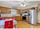 Galley kitchen featuring wood cabinets and stainless steel refrigerator at 5755 Yorkshire Dr, Zephyrhills, FL 33542