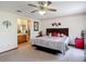 Bright main bedroom featuring a ceiling fan, floral accents, and a view of the ensuite bathroom at 5755 Yorkshire Dr, Zephyrhills, FL 33542
