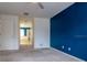 Spacious bedroom with blue accent wall, neutral carpet, and door leading to the bathroom at 5916 Tulip Flower Dr, Riverview, FL 33578