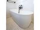 Close up of a modern, standalone bathtub with black faucet fixtures and patterned tile floors at 608 Grove N St, St Petersburg, FL 33701