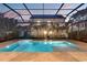 A backyard pool and spa are enclosed with screen and surrounded by travertine tile with palm trees at 608 Grove N St, St Petersburg, FL 33701