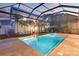 Backyard pool and spa are enclosed with screen, surrounded by travertine tile and lush landscaping at 608 Grove N St, St Petersburg, FL 33701
