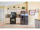 Spacious kitchen with stainless steel refrigerator, black appliances, granite countertops, and ample cabinet space at 6908 Mesa Verde St, Port Richey, FL 34668
