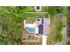 Aerial view showcasing the home's layout with a pool, solar panels, spacious yard, and green surroundings at 807 E Chapman Rd, Lutz, FL 33549
