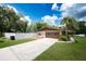 The front exterior highlights a two-car garage, a large driveway, and lush, green grass with partial fencing at 807 E Chapman Rd, Lutz, FL 33549