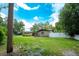 A neatly kept front lawn is in front of this charming ranch-style home under a partly cloudy, bright blue sky at 807 E Chapman Rd, Lutz, FL 33549