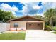 This view captures a tan house with a well-maintained front yard, green grass, and a two-car brown garage door at 807 E Chapman Rd, Lutz, FL 33549