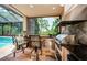 This outdoor kitchen features a built-in grill with a bar and seating overlooking the pool at 1012 Tuscany Dr, Trinity, FL 34655
