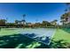 Outdoor tennis court surrounded by lush greenery, featuring a shaded rest area at 1012 Tuscany Dr, Trinity, FL 34655