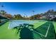 A view of a well maintained outdoor tennis court surrounded by lush landscaping and shade at 1012 Tuscany Dr, Trinity, FL 34655