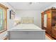 Well-lit bedroom with light walls, an antique wooden dresser, and a comfortable white bed at 10193 Wallien Dr, Brooksville, FL 34601