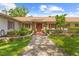 Charming home entrance featuring a stone walkway, lush landscaping, and a welcoming red door at 10193 Wallien Dr, Brooksville, FL 34601