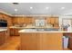 Charming kitchen with oak cabinetry, island cooktop, and decorative wallpaper at 10193 Wallien Dr, Brooksville, FL 34601